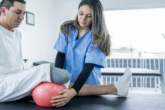 Physical therapist assisting a below-knee amputee with prosthetic rehabilitation exercises to improve strength, balance, and prosthetic success